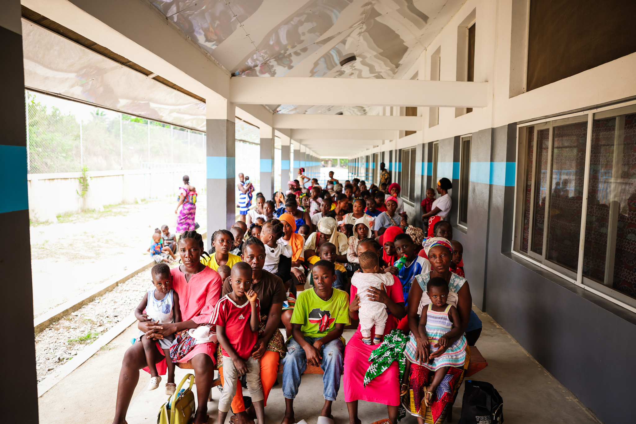Mothers and children wait on the porch for their turn to be seen at the Jesus Loves Me Children's Center