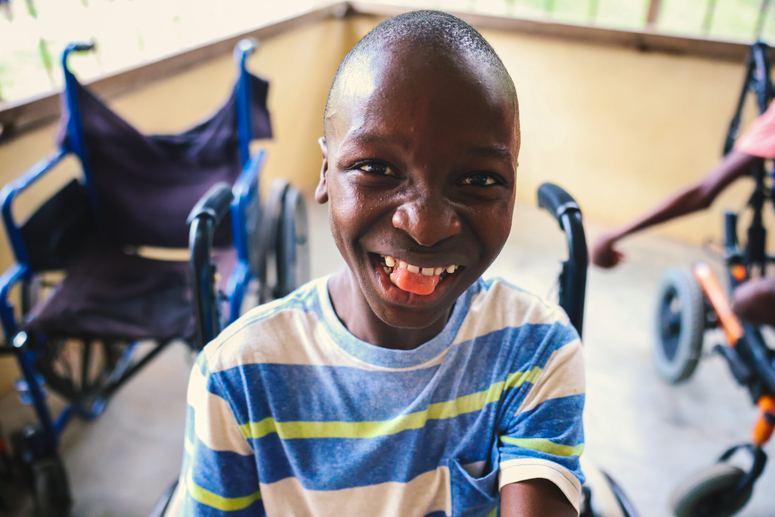 A boy in a striped shirt grins on the porch.