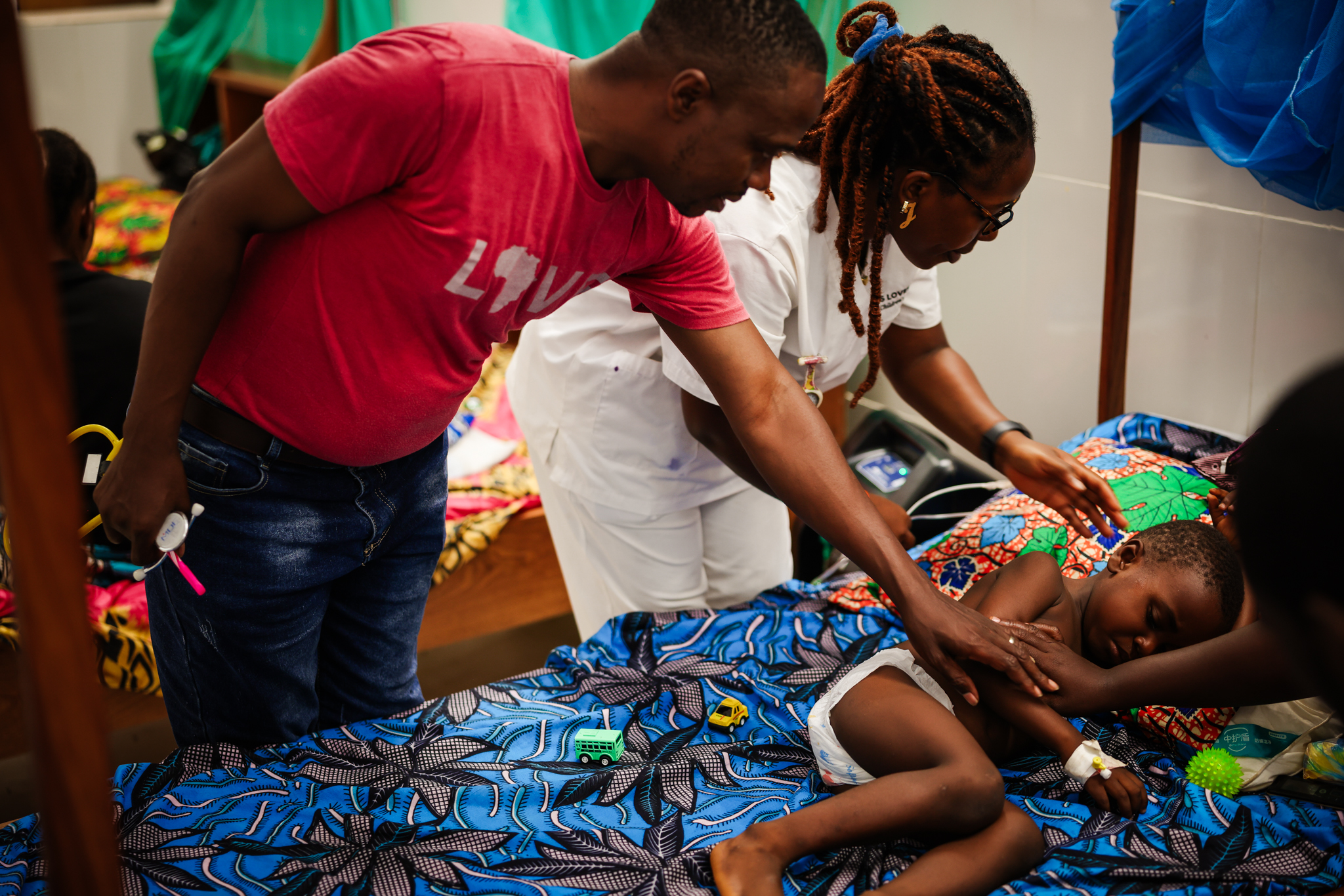 Liberian nurses examine a young child as her mother holds her on the ward at the Jesus Loves Me Children's Center