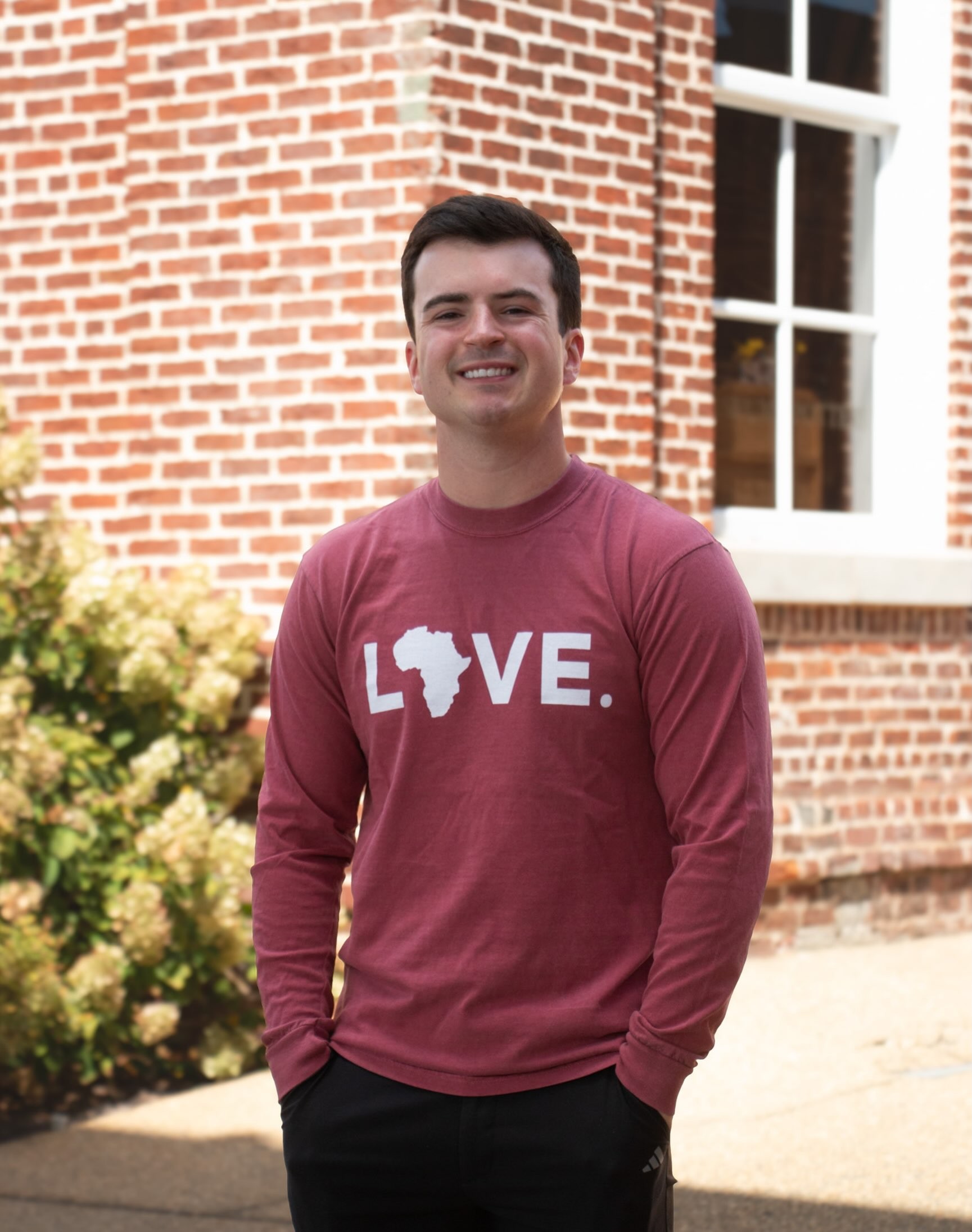 A young man in a maroon LOVE. tee.