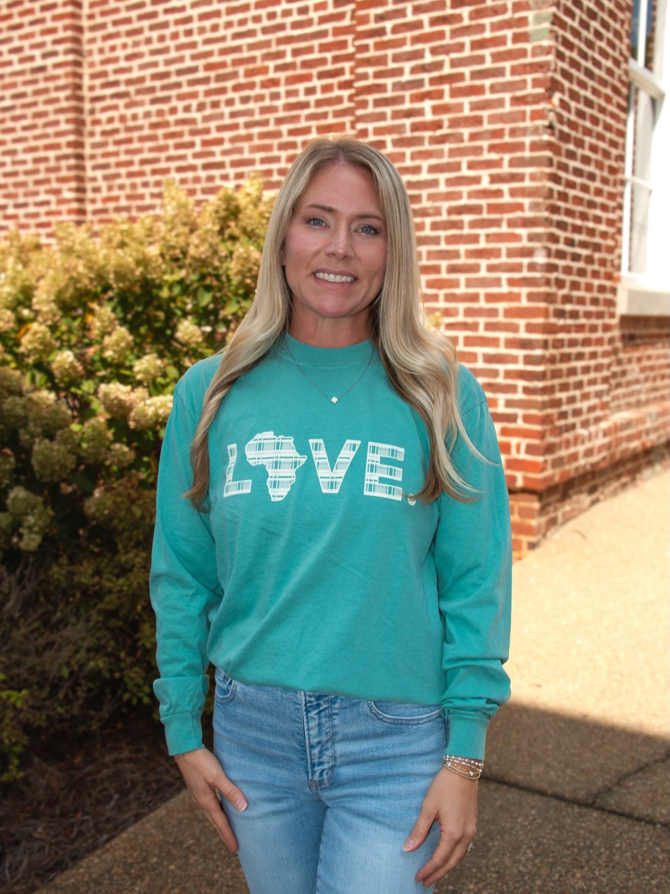 A woman in a teal LOVE. sweatshirt.